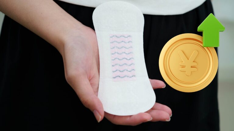 A hand holding a white sanitary pad beside a gold yen coin and a green upward arrow signaling a price increase.