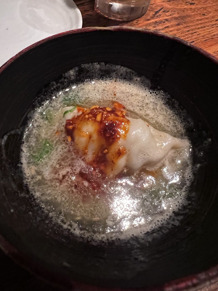 A gyoza dumpling simmering in broth