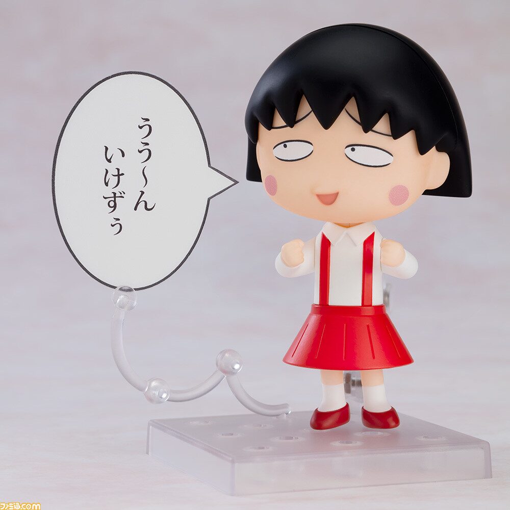 A Nendoroid figure of anime character Chibi Maruko-chan with a speech bubble reading her catchphrase "うう〜ん、いけずぅ."