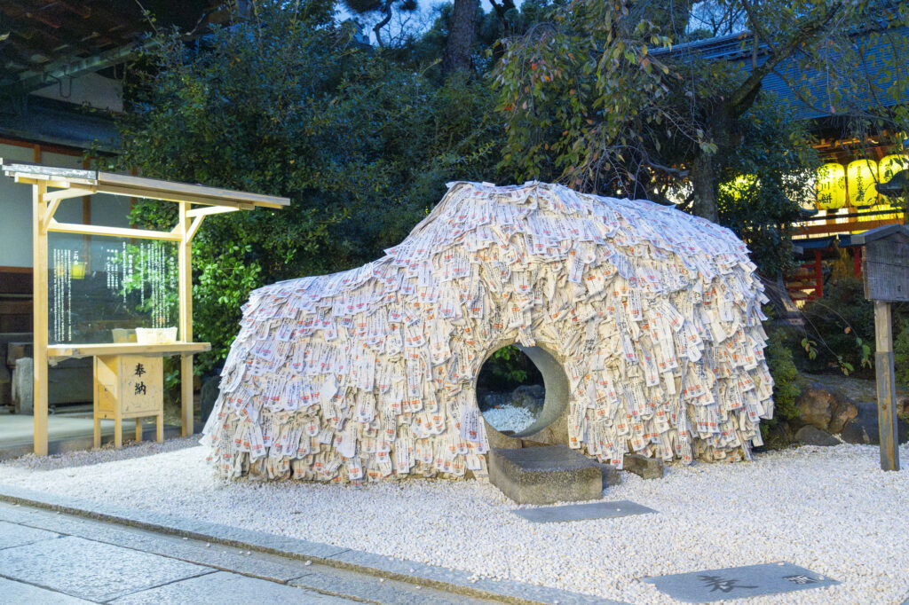 The bond-severing stone at Yasui Konpiragū, a mound blanketed in white paper prayer slips with a crawl-through hole