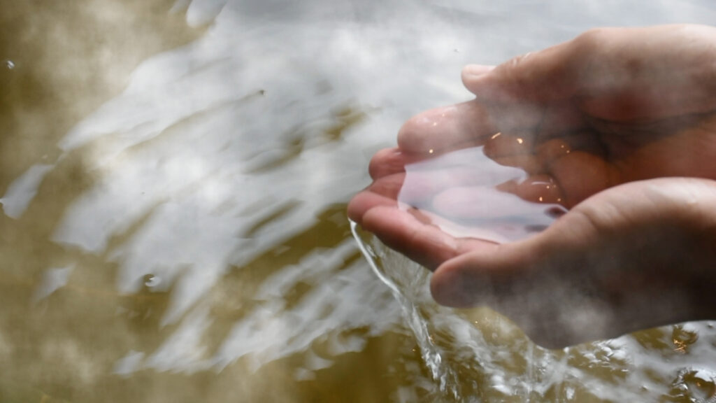 Cupped hands catching steaming bathwater