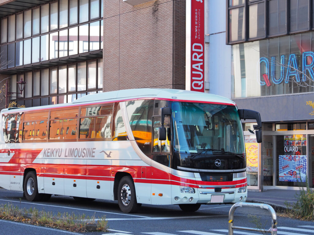 A red and white Keikyu Limousine highway bus parked on a city street
