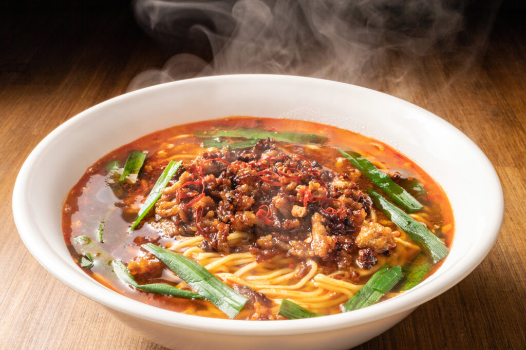 A steaming bowl of Nagoya's spicy Taiwan ramen: noodles in red chili broth topped with spiced ground meat and green chives
