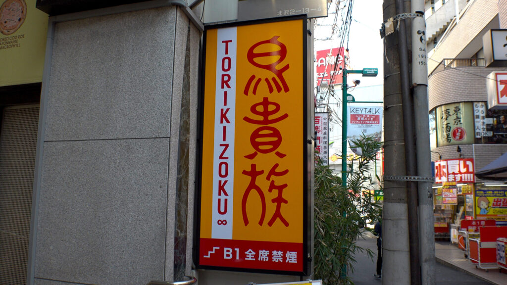 Illuminated Torikizoku yakitori-chain street sign on a Tokyo shopping street.