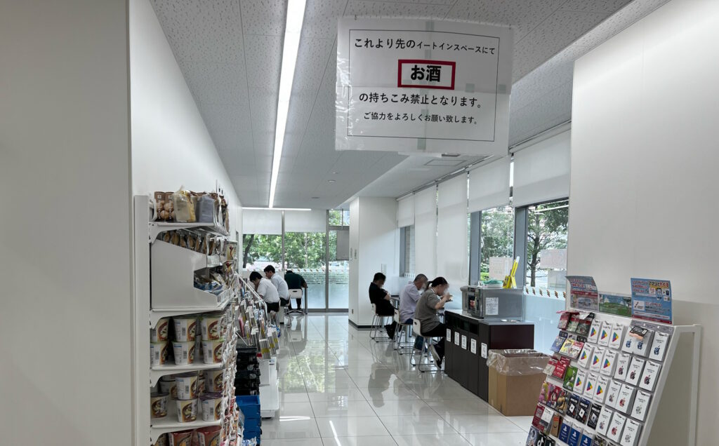 Interior of the Samezu Seaside 7-Eleven, showing its eat-in seating area with customers and food shelving