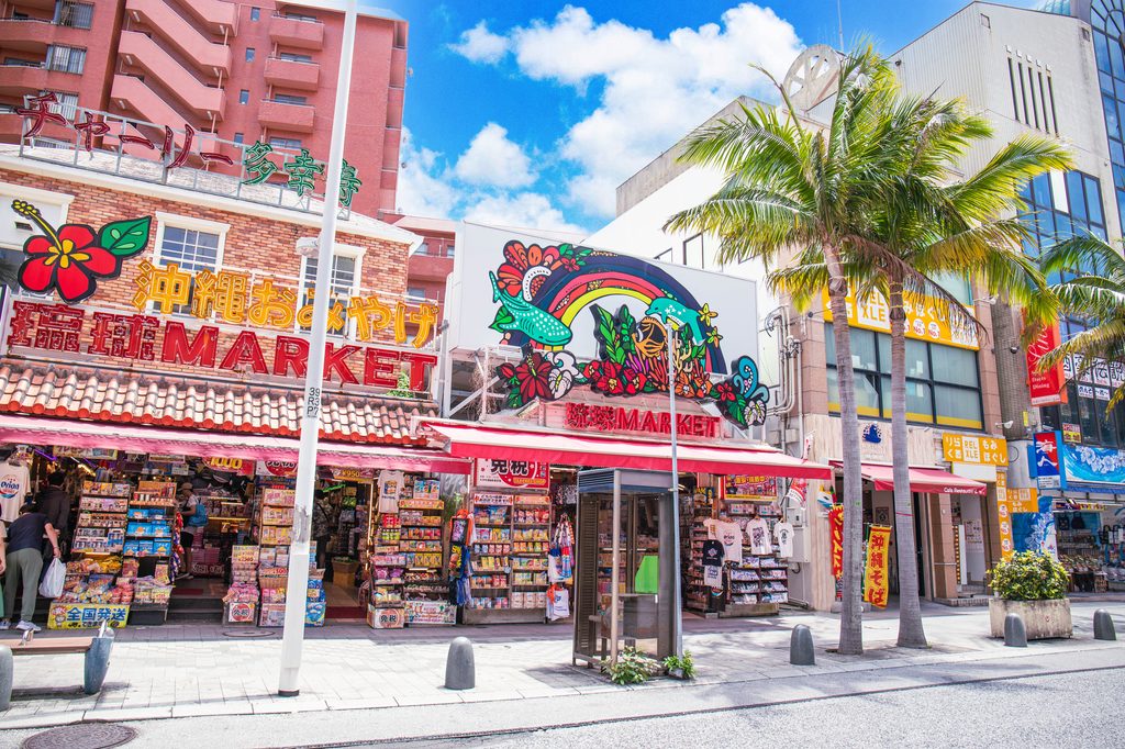 Souvenir shops with hibiscus signs and palm trees along Kokusai-dōri, Naha's main shopping street