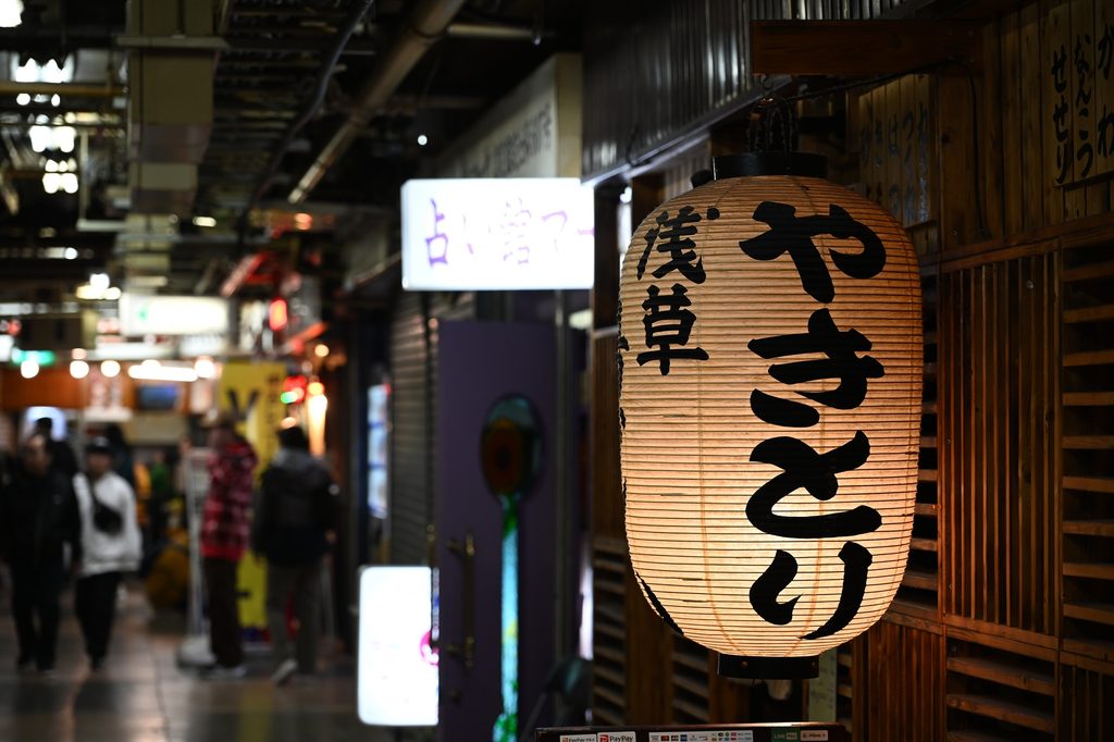 A paper lantern reading "yakitori" and "Asakusa" hangs outside a shop in a covered arcade.