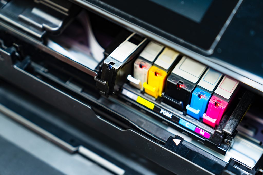 Cyan, magenta, yellow and black ink cartridges seated in an open printer carriage.