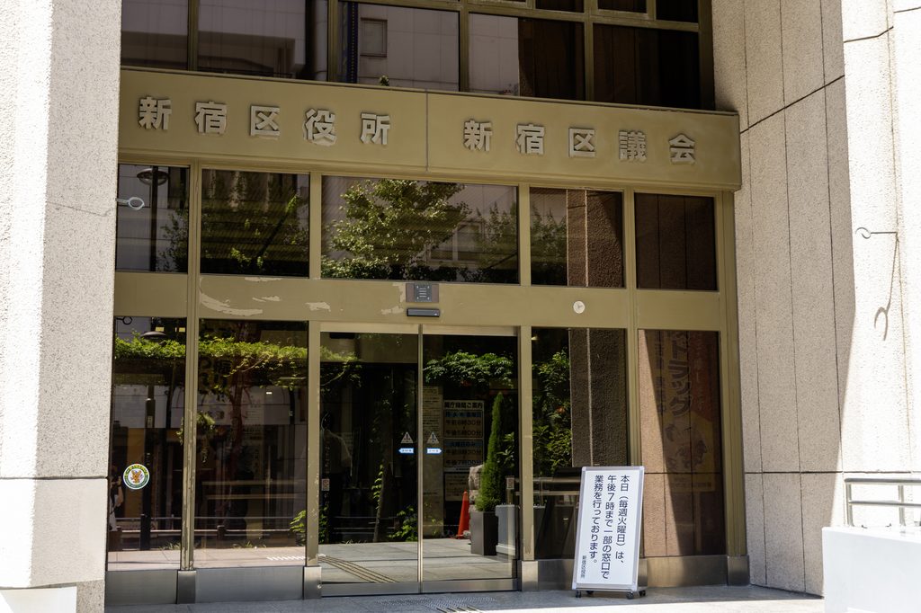 The entrance to the Shinjuku Ward Office and Ward Assembly building, its name in kanji across the facade.
