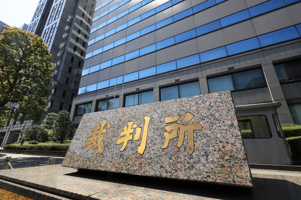 Granite sign reading 裁判所 (courthouse) in gold characters outside a Japanese court building