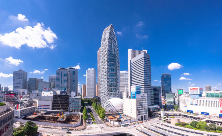The Shinjuku skyline on a clear day, with the Mode Gakuen Cocoon Tower at center and Odakyu and Bic Camera signage at right.
