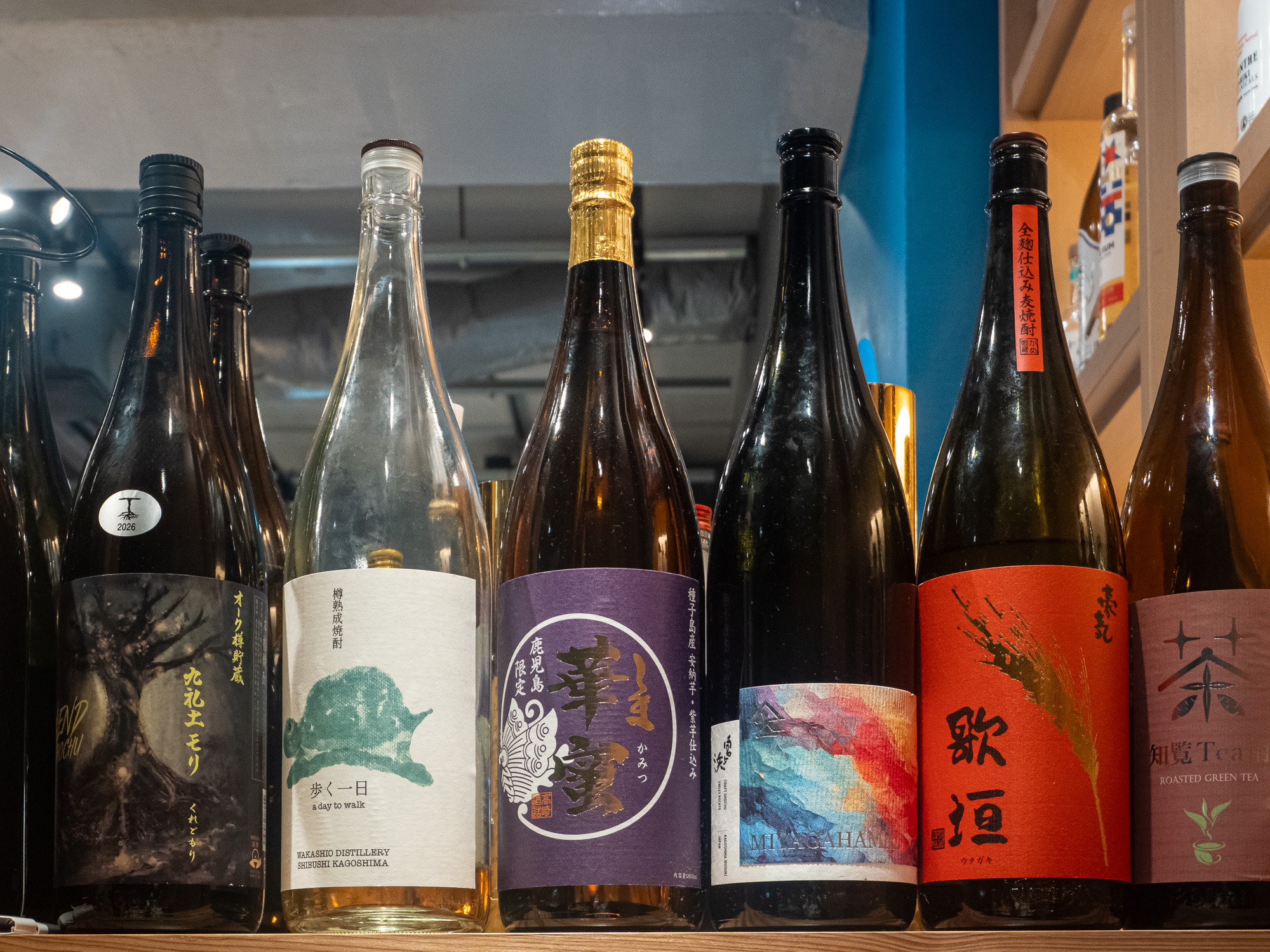 A row of sake and shochu bottles on a shelf inside a Yūrakuchō izakaya