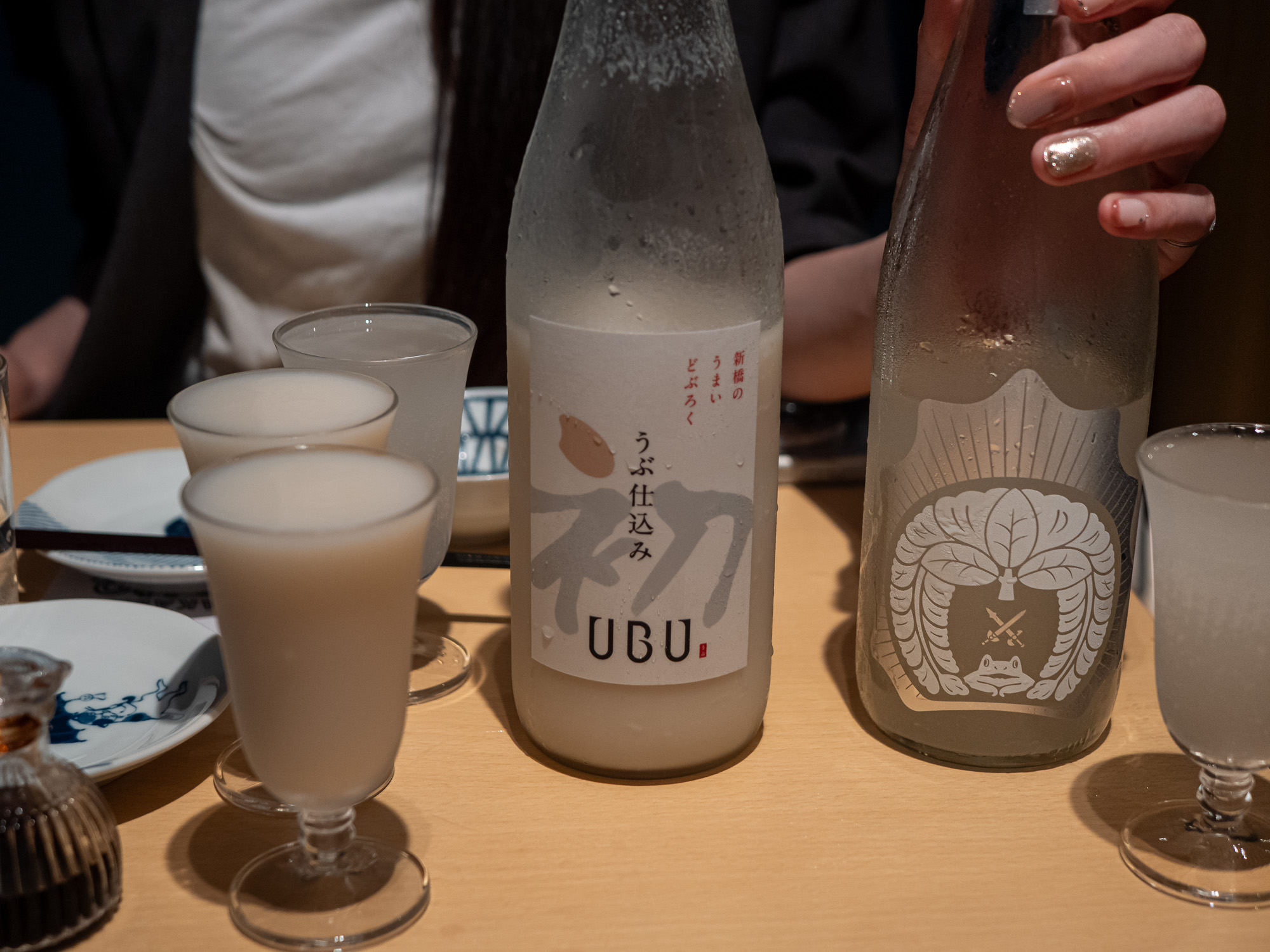 Two styles of nigori sake side by side, one thick and cloudy, one light and clear