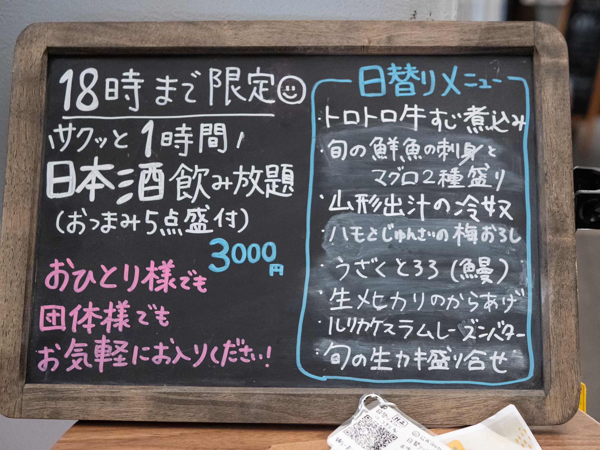 A chalkboard menu outside a Yūrakuchō izakaya listing an all-you-can-drink sake course