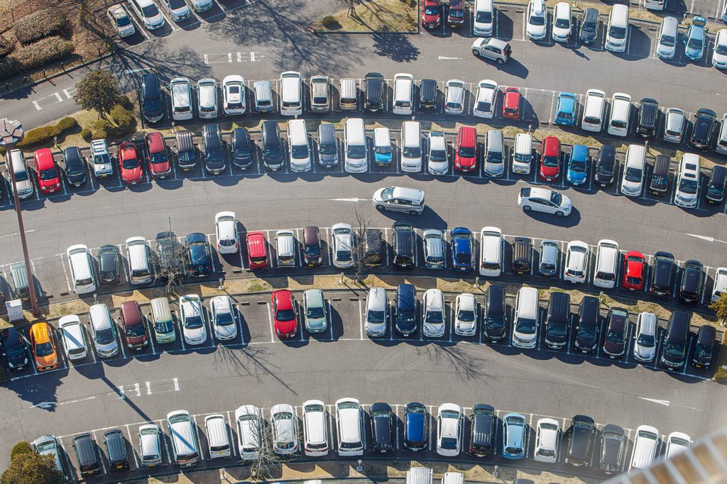 Aerial view of a large parking lot filled with rows of cars