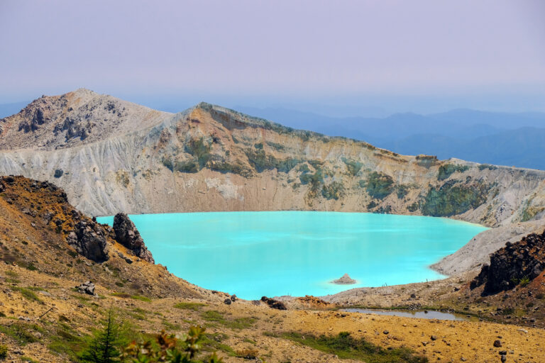 Yugama, a turquoise crater lake ringed by pale, rocky volcanic walls on Kusatsu-Shiranesan