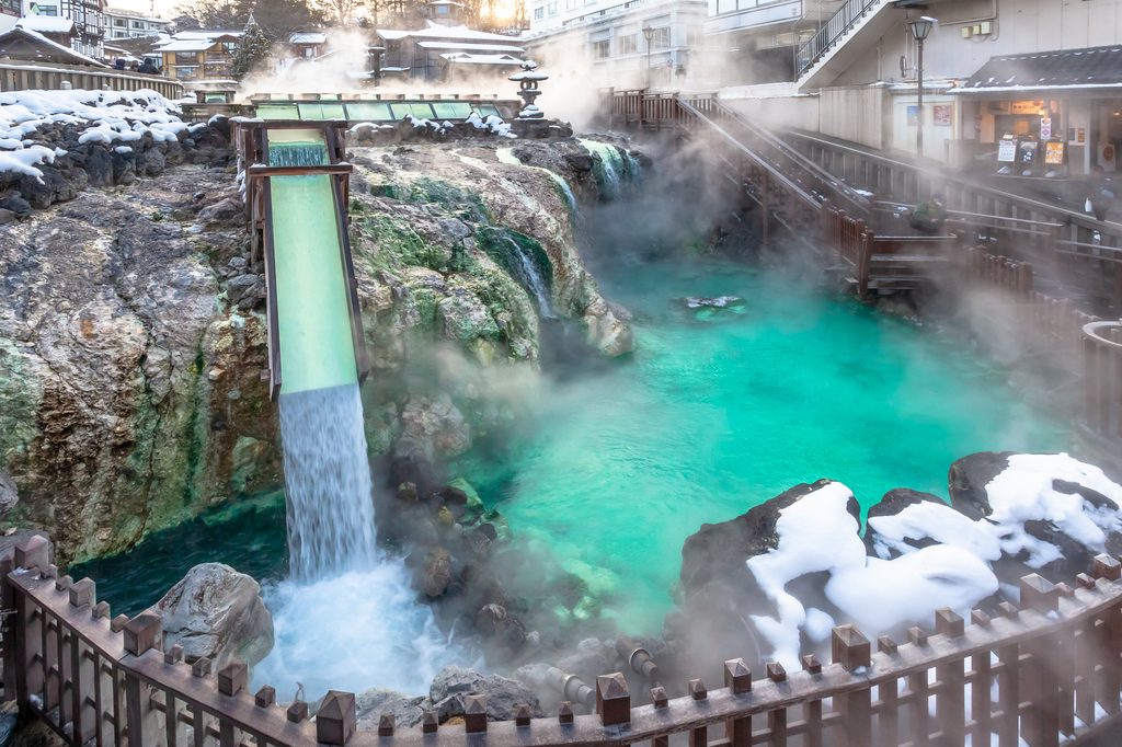 Steam rising from Kusatsu Onsen's Yubatake hot-spring field, with snow on the surrounding rocks