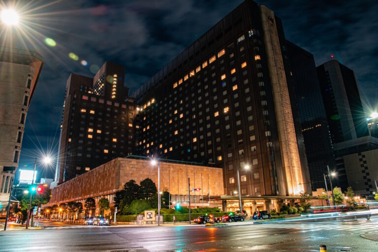 The Imperial Hotel, Tokyo, its high-rise towers lit up at night above a wet street in Uchisaiwaichō